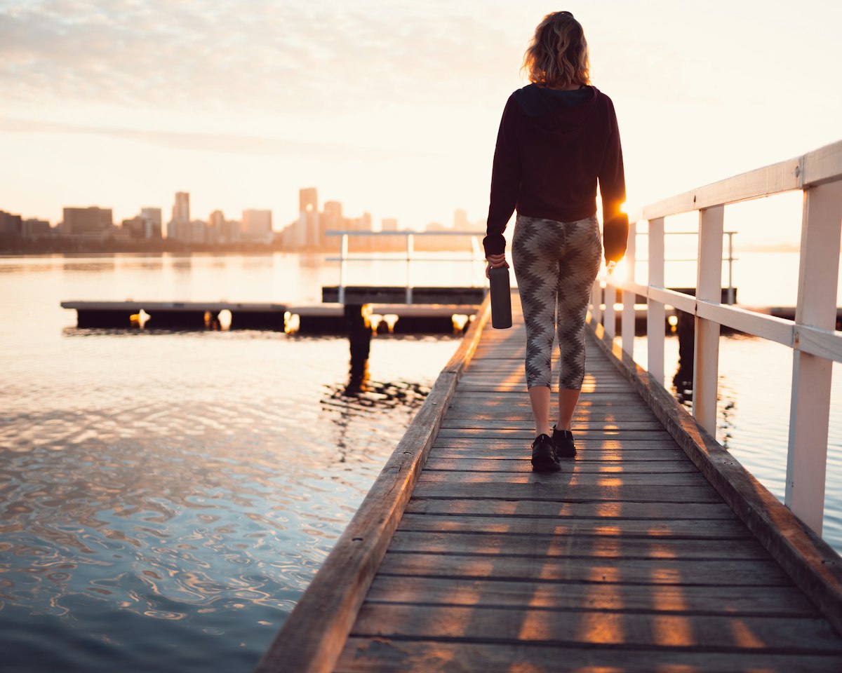 Formation Passerelle : une femme avance sur un ponton vers la lumière du matin