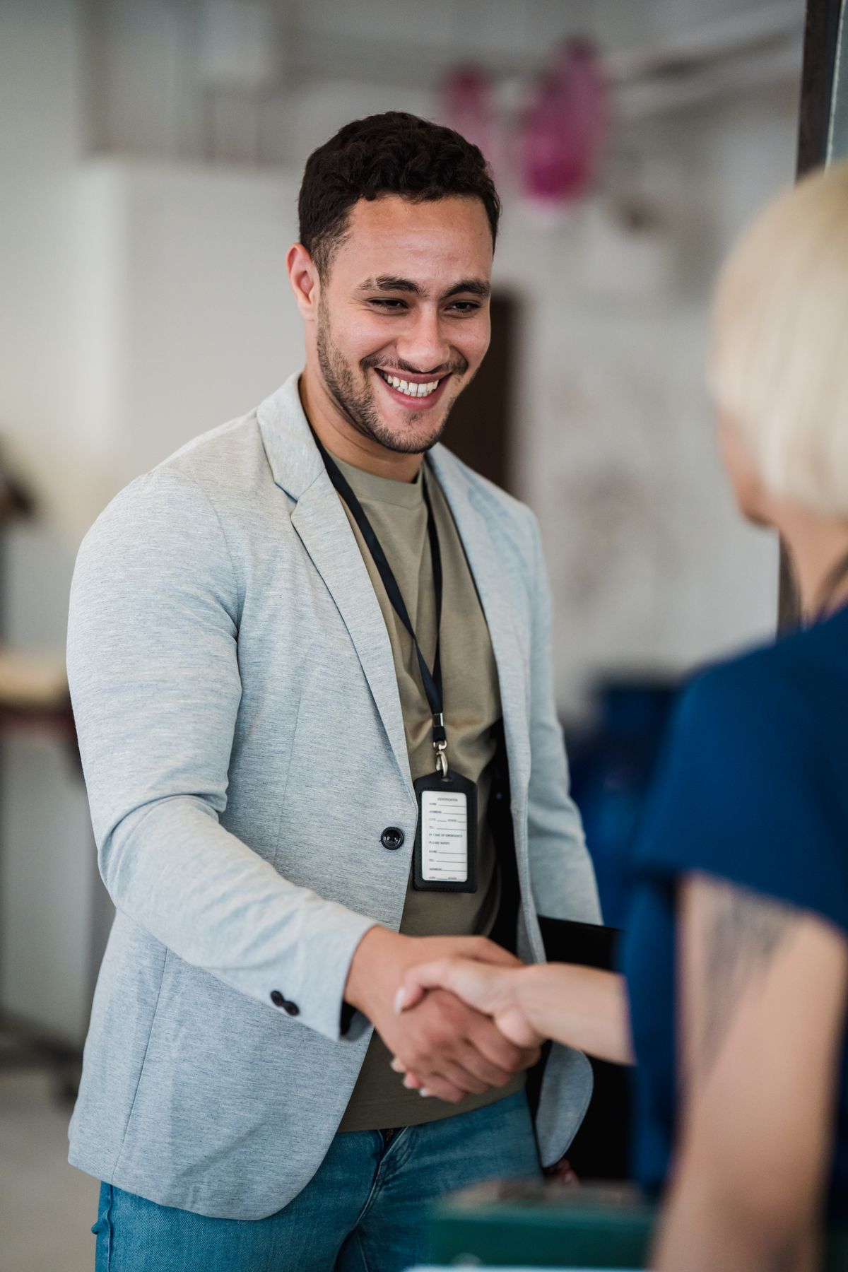 Un jeune homme avec un badge d’entreprise accueilli d’une poignée de main : immersion en entreprise